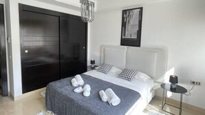 A modern hotel room with a large bed, a black wardrobe, a bedside table with a lamp, and a framed picture on the wall. - Black White Modern Spacious (Tunis)