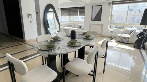 A dining area with a round table, white chairs, and a large mirror. - Black White Modern Spacious (Tunis)