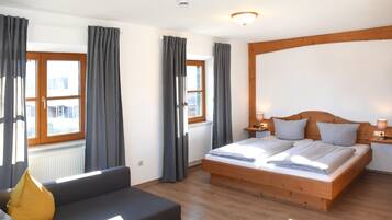Une chambre à coucher avec un lit en bois, des rideaux gris, un canapé et une fenêtre donnant sur un beau paysage.