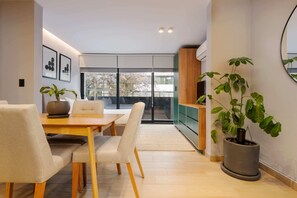 Enjoy a spacious dining area with a table and comfortable seating, leading to a balcony with a city view.