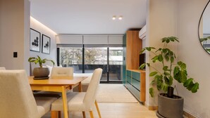A modern dining area with a wooden table and chairs, a potted plant, and a view through glass doors to an outdoor space. - w* | Captivating Loft with Terrace in Polanco (Ciudad de México)