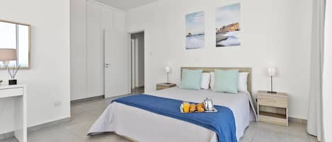 A modern hotel room with a large bed, bedside tables, a desk, and a mirror.