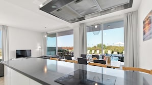Une cuisine moderne dotée d’un grand îlot central, d’une cuisinière intégrée et d’un coin repas avec des chaises et des tables.
