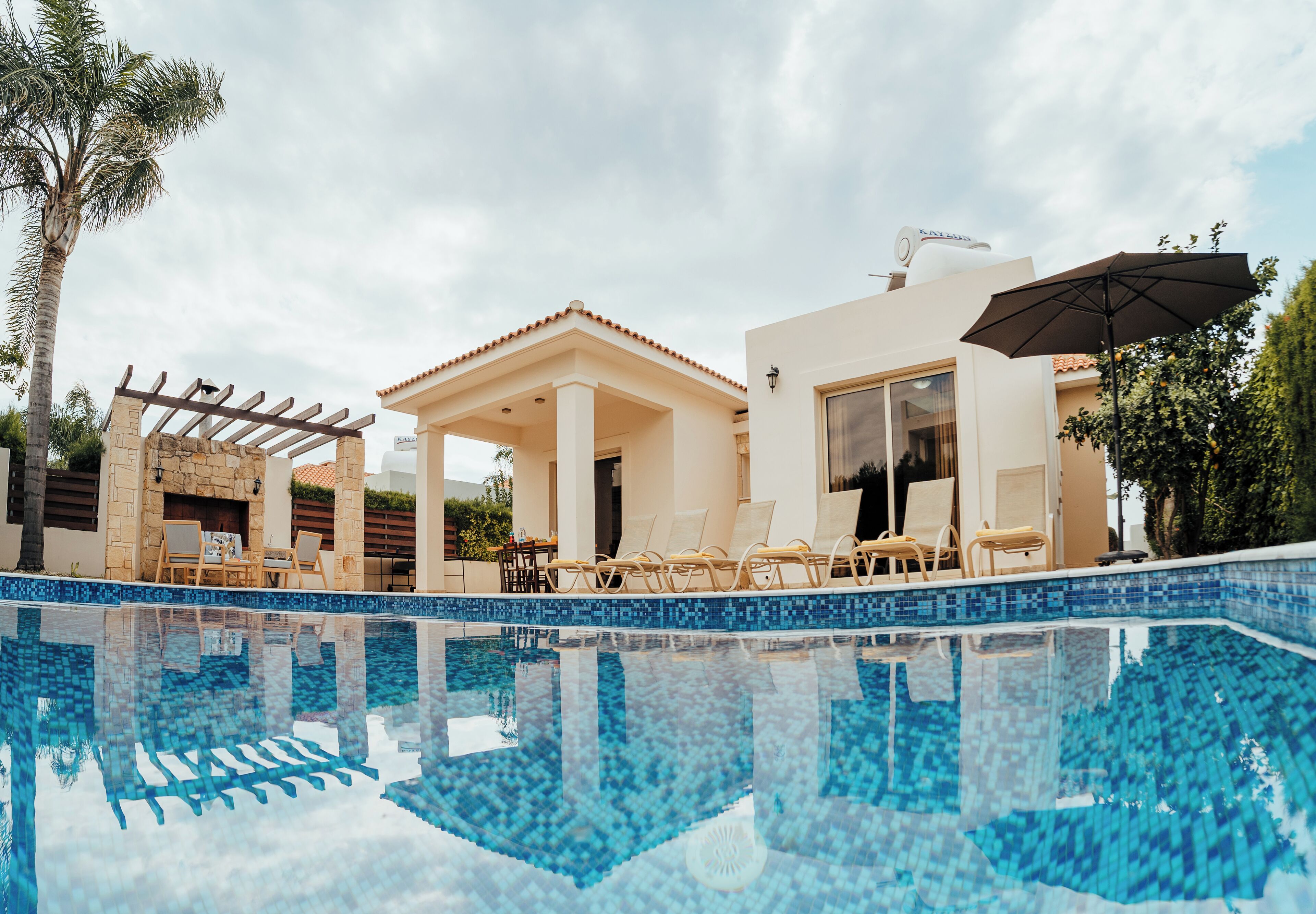 A modern pool area with clear blue water, lounge chairs, and a pergola structure.