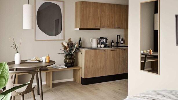 Una cocina moderna con armarios de madera, un comedor con mesa y sillas redondas, y un espejo grande en la pared.