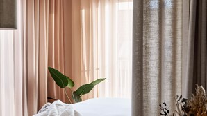 Ein Hotelzimmer mit einem Bett, einem Tisch mit Dessert und einem Fenster mit Vorhängen.