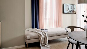 Ein modernes Wohnzimmer mit einer Couch, einem Esstisch und einem großen Fenster mit transparenten Vorhängen.