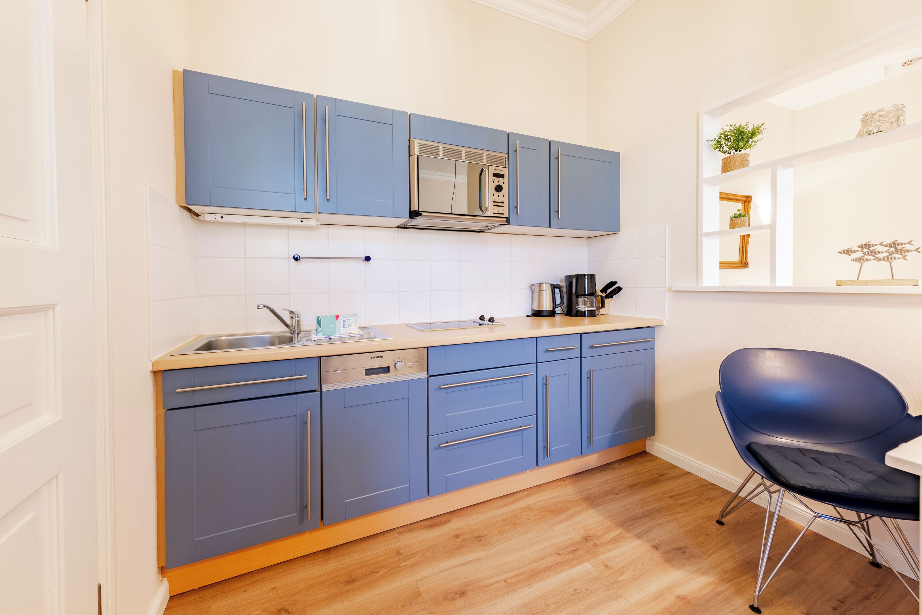 A modern kitchen with blue cabinets, a stainless steel microwave, and a coffee maker.
