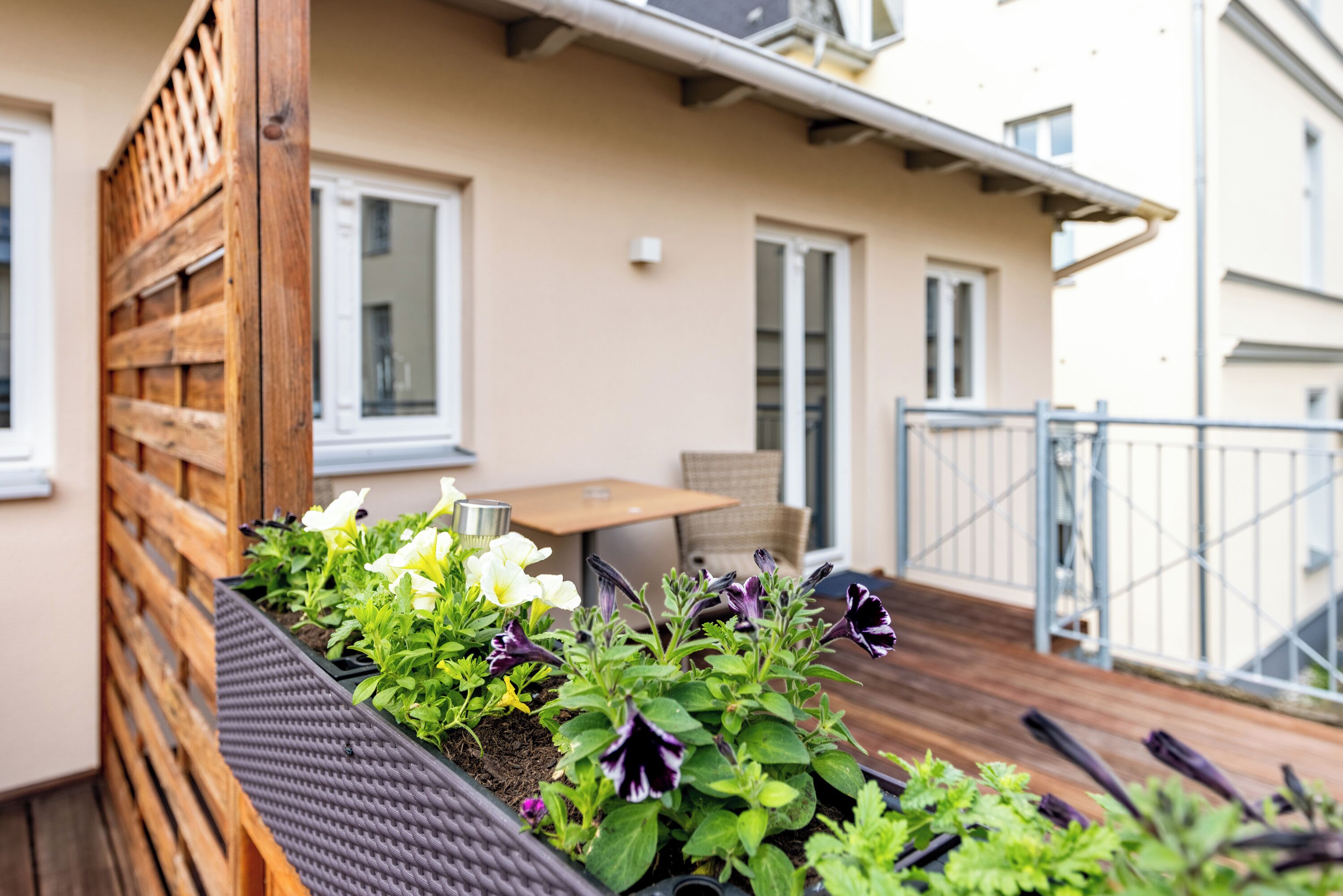 A balcony with a wooden trellis, a small table, and chairs.