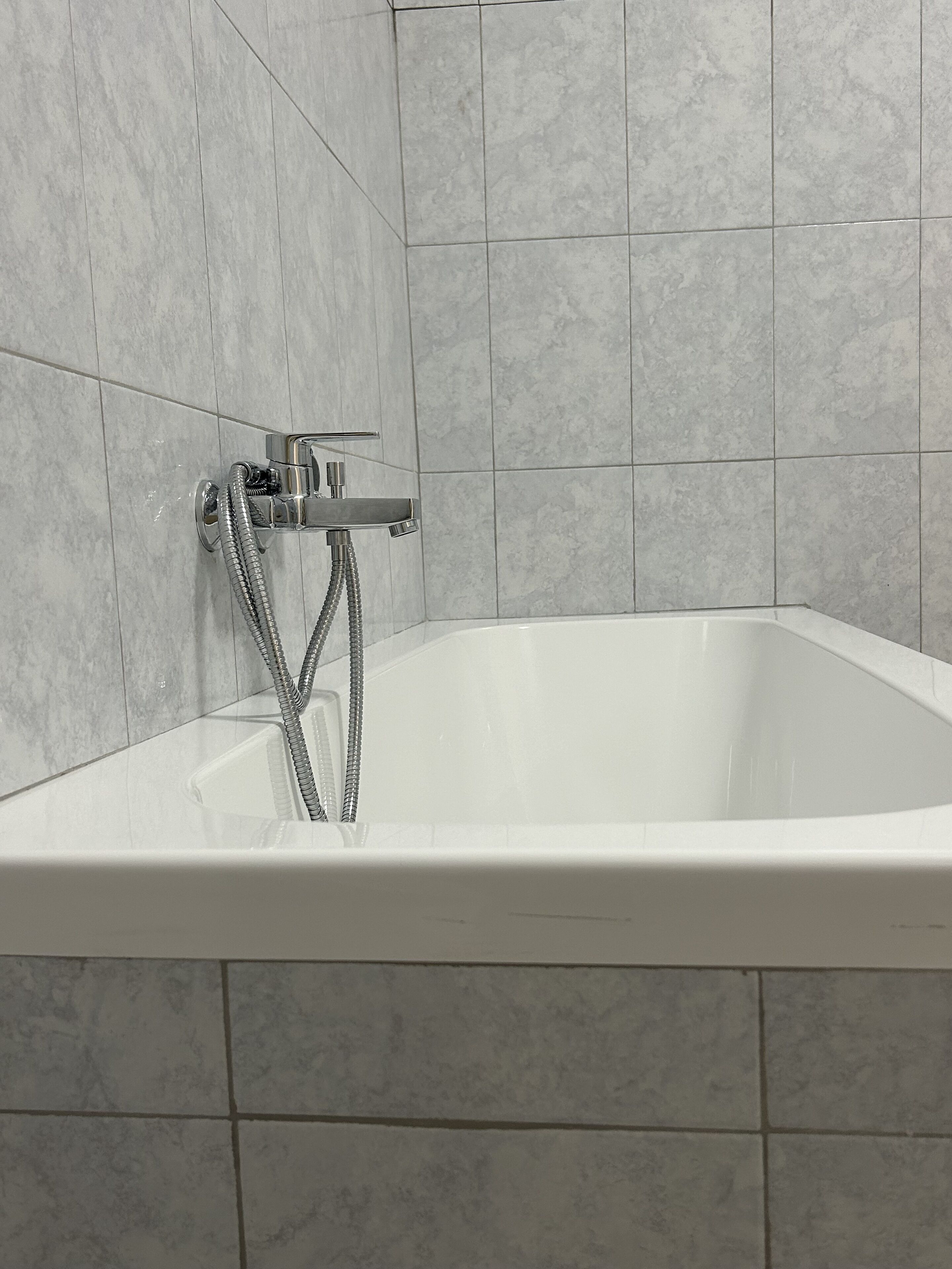 A modern bathroom with a freestanding bathtub, chrome fixtures, and tiled walls.