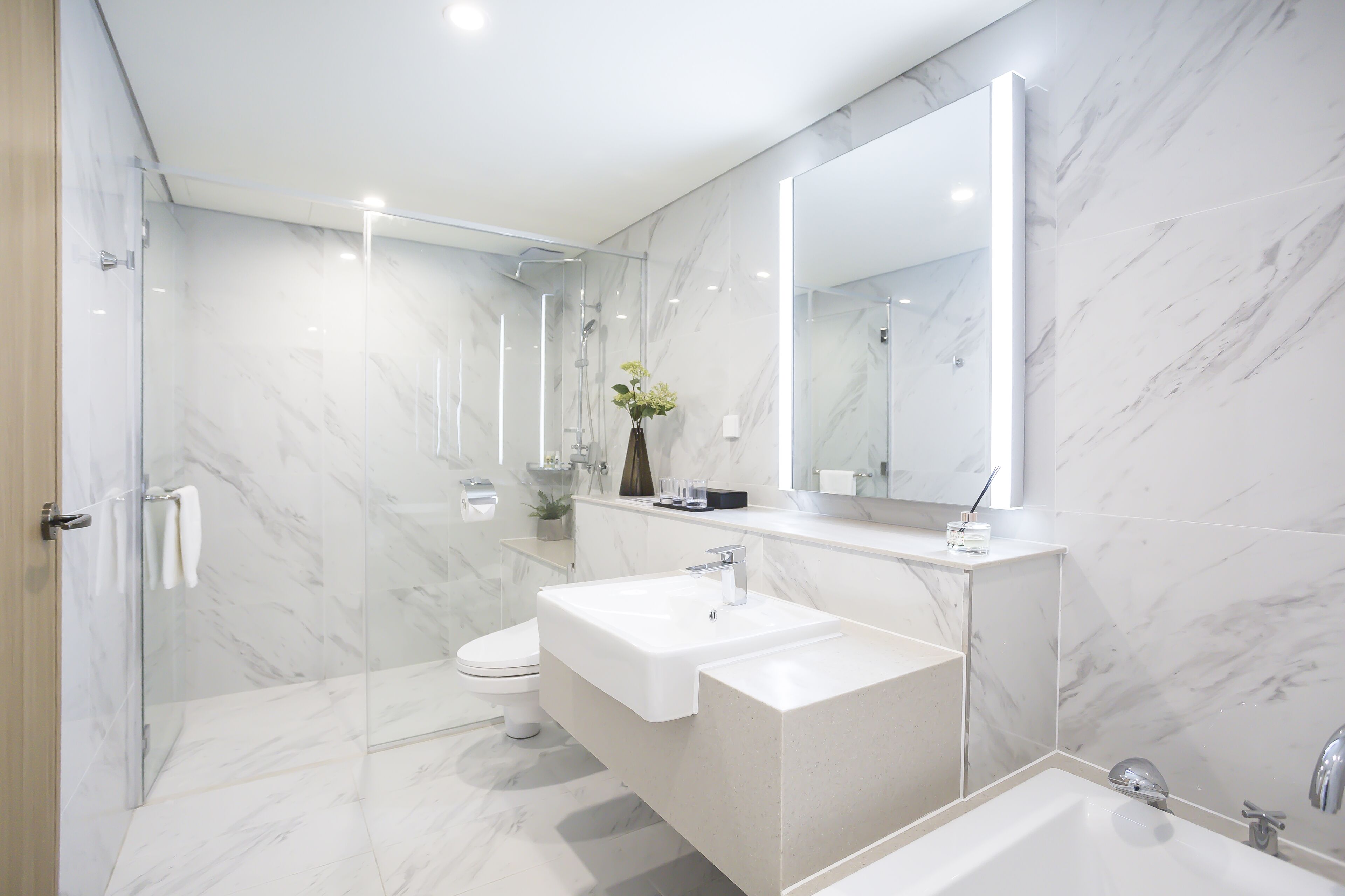 Un baño moderno con cabina de ducha de vidrio, un lavabo blanco y un espejo grande.