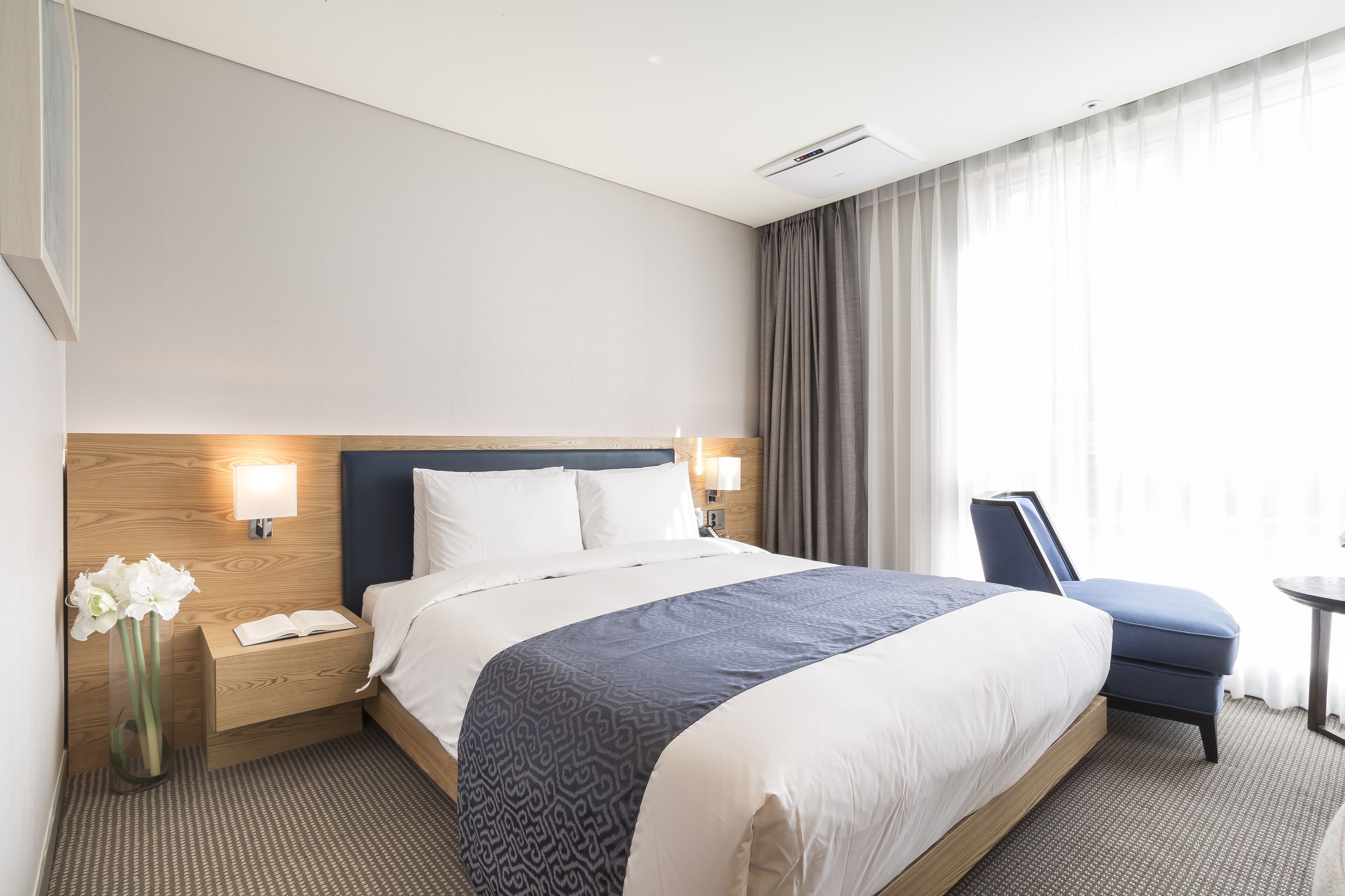 Ein Hotelzimmer mit einem großen Bett, Nachttischen, einem Sessel und einem kleinen Tisch.