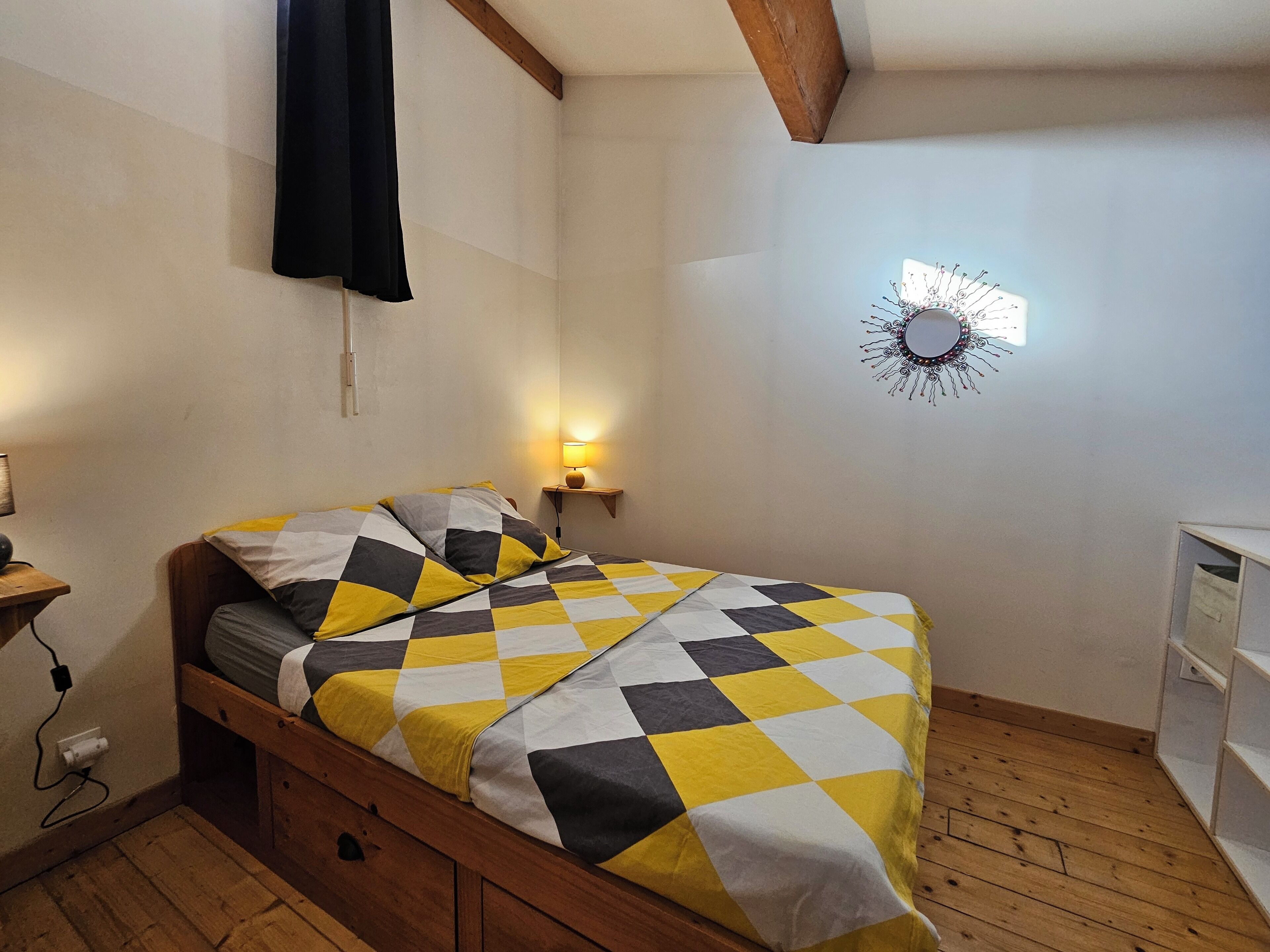 Ein Schlafzimmer mit Bett, Holzboden, einer Wandleuchte und einem Wandbild.