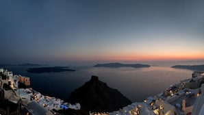 A coastal hotel with white buildings, a view of the sea, and a sunset. - Artemis Villas (Santorini)