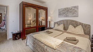 Un dormitorio con una cama grande, un armario, una mesita de noche con lámparas y un cuadro en la pared.