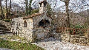 Una estructura de piedra con una chimenea, un pequeño ventanal de arco y una barandilla de metal.
