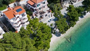 An aerial view of a coastal residential area with multi-story buildings, a clear beach, and a road running parallel to the shore.