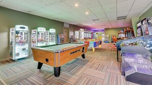 A room with pool tables, claw machines, and arcade games.