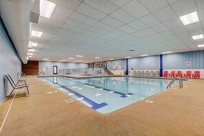 An indoor swimming pool with clear lane markings, a wooden wall, and red chairs along the side. - The Getaway at Tamarack (Wisconsin Dells)