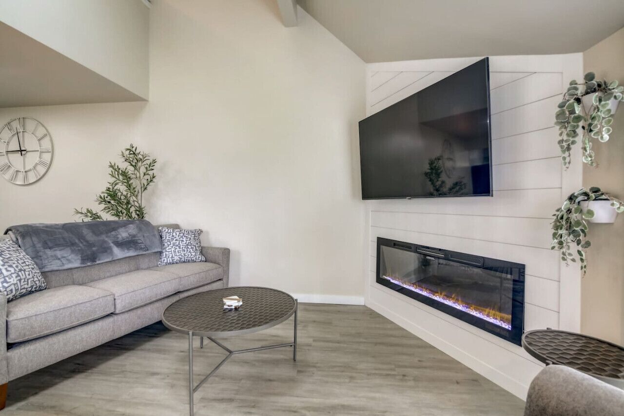 Un salon comprenant un canapé, une table basse, une cheminée et un téléviseur à écran plat fixé au mur.