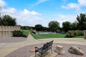 A park with a paved walkway, a bench, and a small pool area.