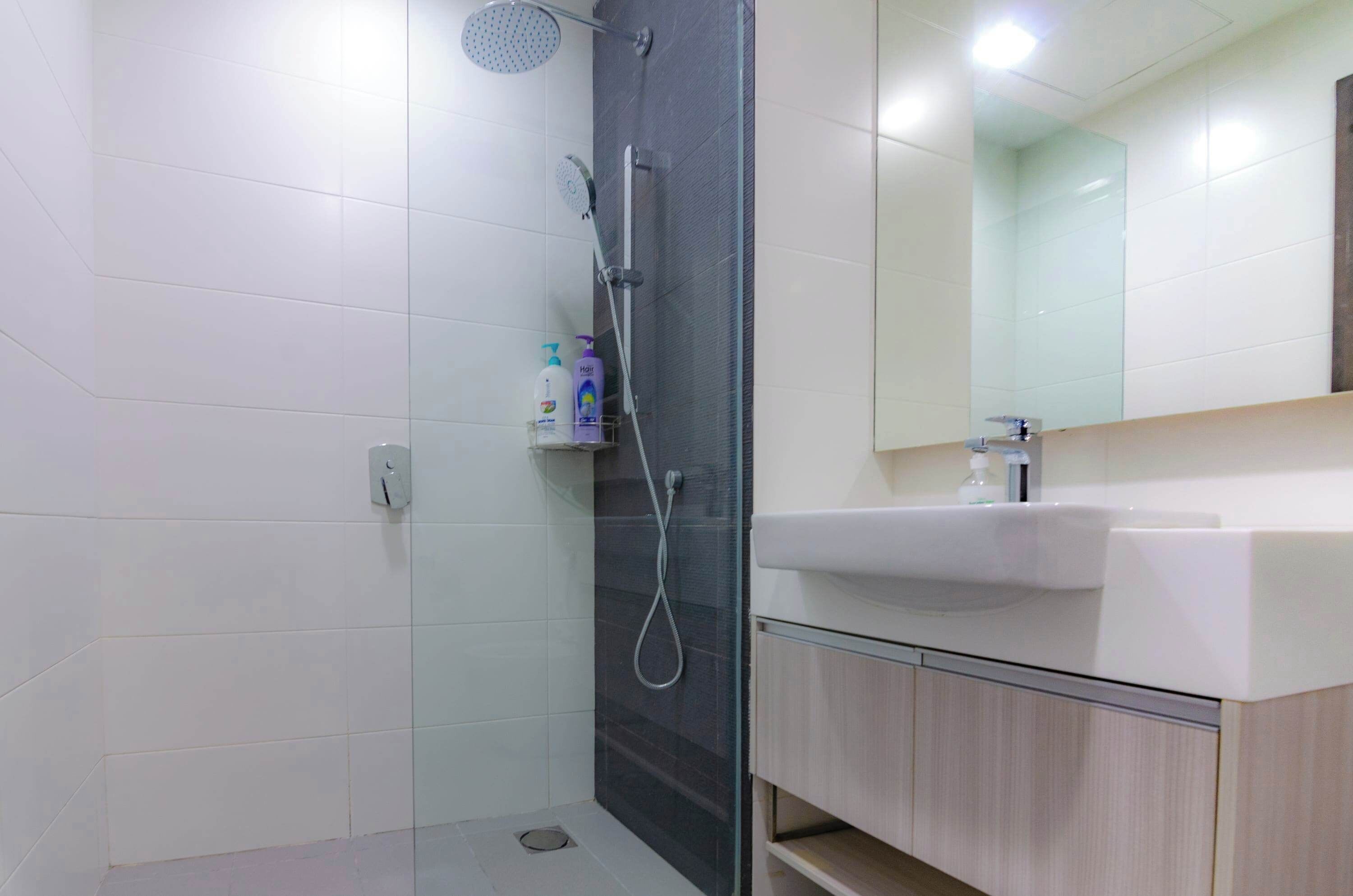Un baño moderno con cabina de ducha de vidrio, un lavabo blanco y un espejo sobre el lavabo.