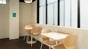 A modern, well-lit room with a large window, a wooden table, and four chairs. - Bobopod Thamrin, Jakarta (Jakarta)