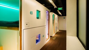 A hotel corridor with numbered rooms, a green exit sign, and a wooden floor. - Bobopod Thamrin, Jakarta (Jakarta)