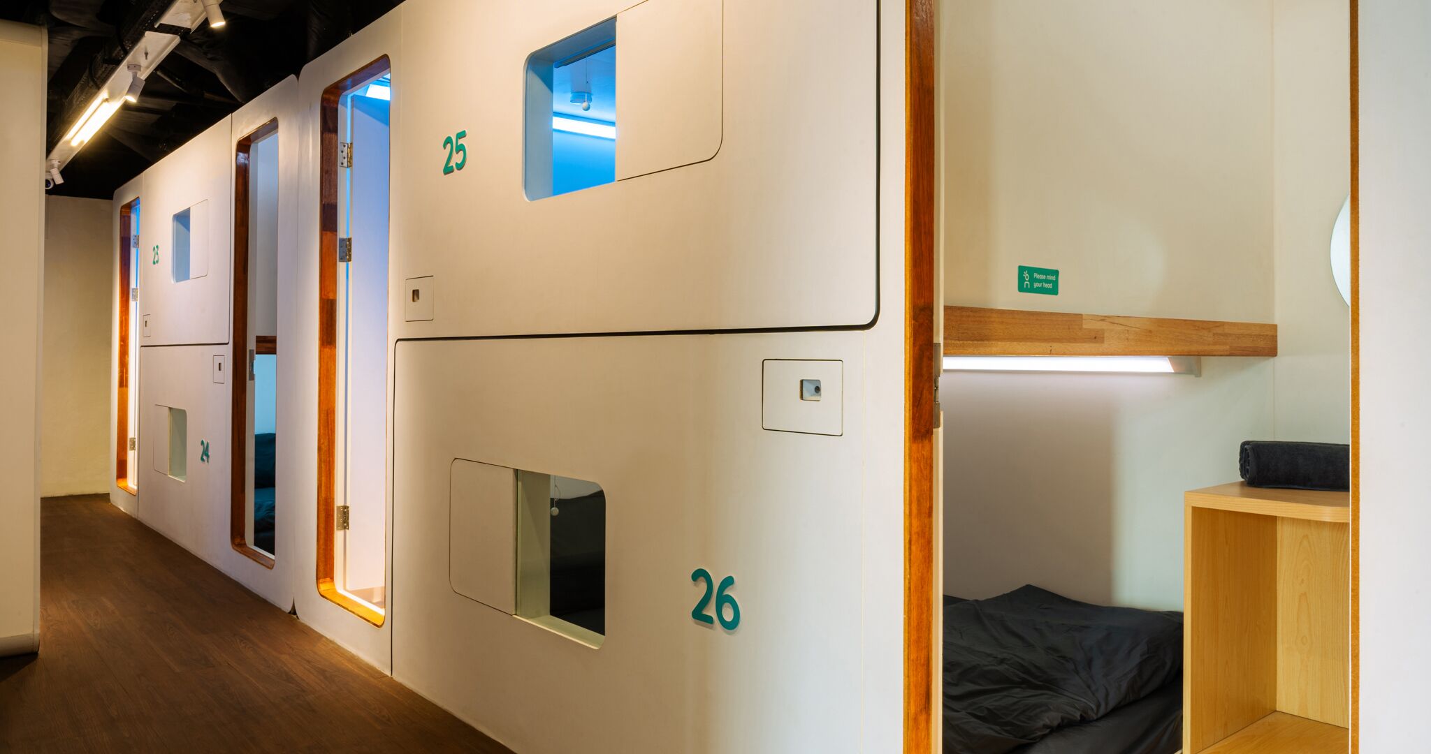 Un couloir d’hôtel avec des portes numérotées, un banc en bois et une petite étagère sur laquelle est posée une serviette.
