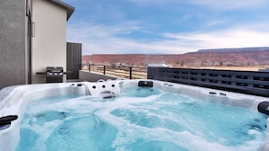 A hot tub on a balcony with a view of a mountainous landscape.