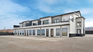 A modern two-story building with a flat roof, large windows, and a balcony on the upper floor.
