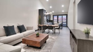 Uma sala de estar moderna com sofá, mesa de centro e área de jantar.