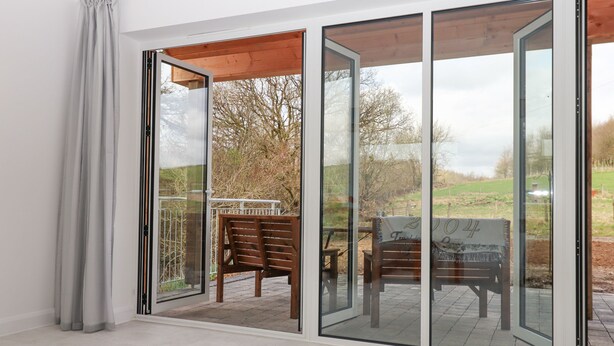 A room with a large sliding glass door leading to an outdoor patio area. - Narracott Down (South Molton)