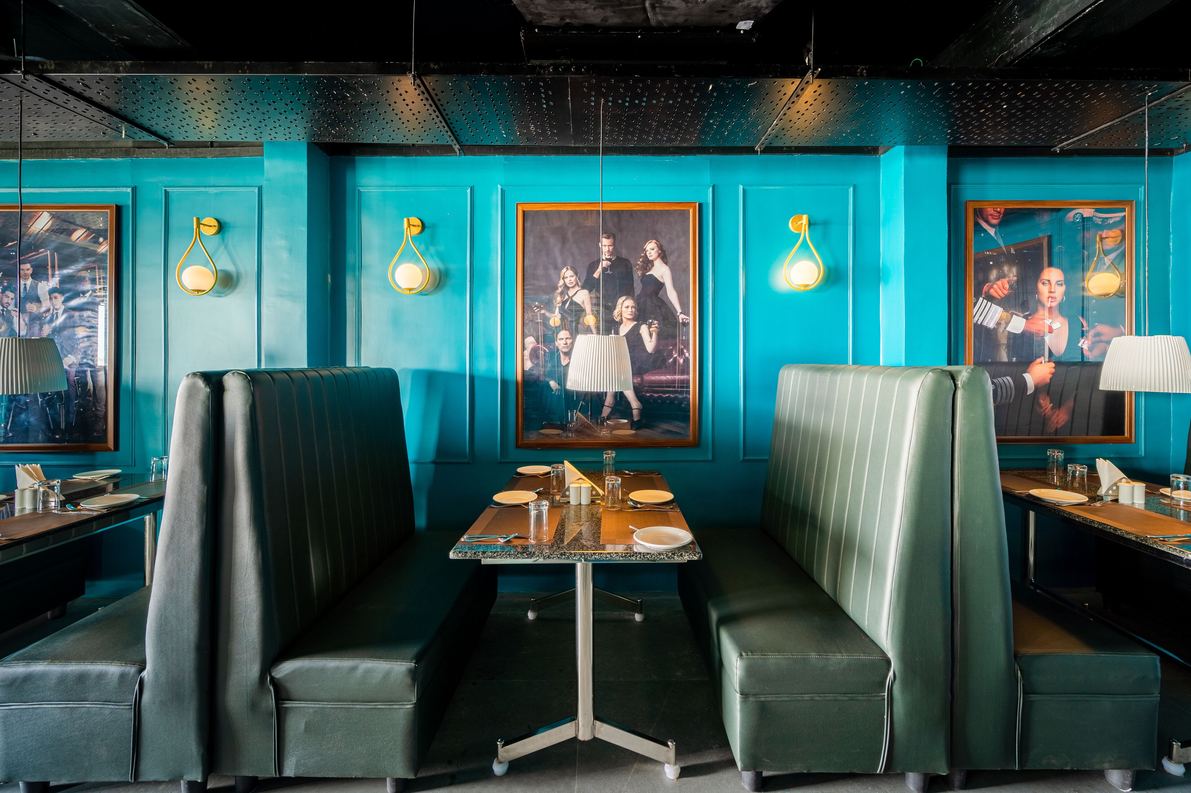 Um restaurante com paredes verde-água, assentos em verde e quadros decorativos nas paredes.