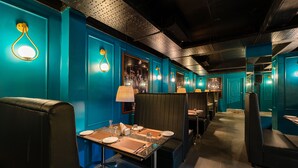 A restaurant with teal walls, black booths, and a long counter with tables set for dining. - Rolling space (Puducherry)