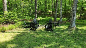 Ett skogsområde med tre Adirondack-stolar placerade i en cirkel.