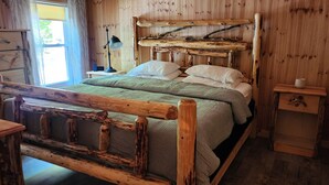 Ett rustikt rum med träpanel, en säng, ett nattduksbord och en byrå.