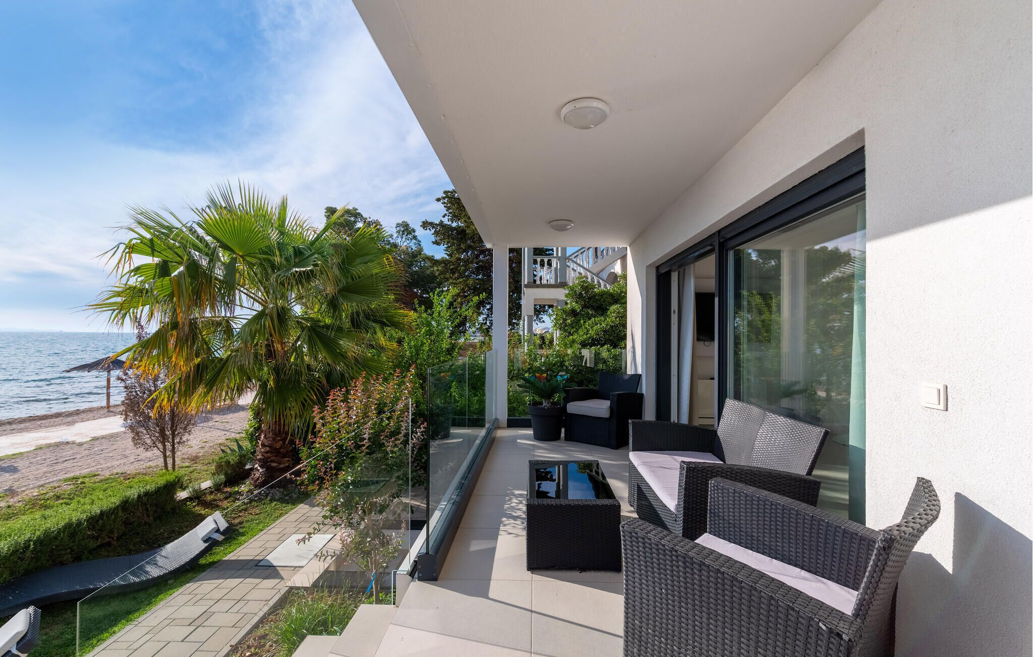 A balcony with wicker furniture, a glass door, and a view of the sea.