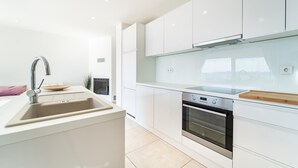 Een moderne keuken met witte kastjes, een roestvrijstalen spoelbak, een ingebouwde oven en een glazen achterwand.