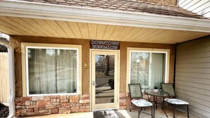 A 'Downtown Bungalow' entrance with a stone facade, large windows, and a small patio with chairs. - Haven at Hazel~Downtown Bungalow, cozy quarters for up to four, farmhouse chic. (Demorest)