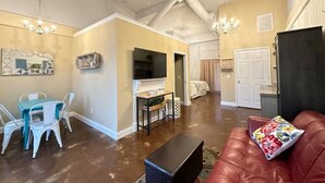 A spacious living area with a dining table, chairs, a red leather sofa, and a television. - Haven at Hazel~Downtown Bungalow, cozy quarters for up to four, farmhouse chic. (Demorest)