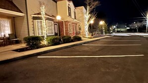 A parking lot with a building featuring a covered patio area and decorative lighting. - Haven at Hazel~Downtown Bungalow, cozy quarters for up to four, farmhouse chic. (Demorest)