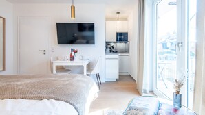 Habitación de hotel moderna con una cama grande, un escritorio, un televisor de pantalla plana y vistas a la ciudad desde la ventana.