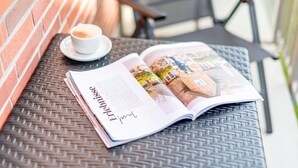 Una revista abierta sobre una mesa de mimbre con una taza de café al lado.