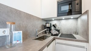 Una cocina moderna con microondas Siemens, pileta de acero inoxidable y cafetera.