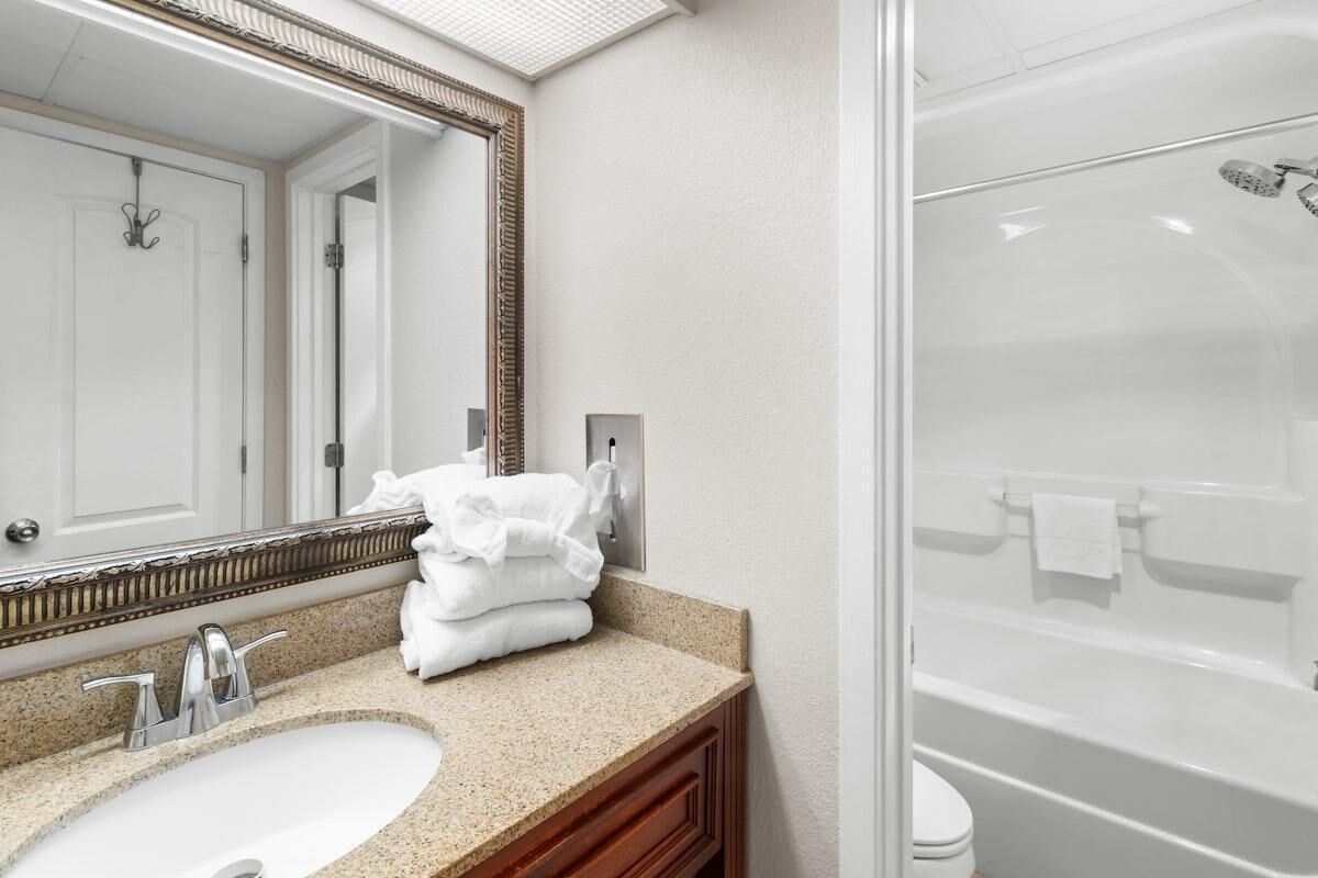 A bathroom with a sink, mirror, and a shower.