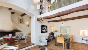 Un amplio espacio de estar con chimenea, una mesa de comedor y diferentes opciones de asiento.