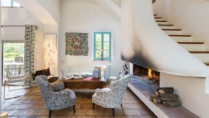 Amplia sala de estar con chimenea, una escalera y vistas al exterior.