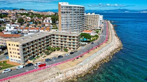 Ein Küstenhotel mit mehreren Gebäuden, einer Straße mit Radweg und freiem Blick auf das Meer.