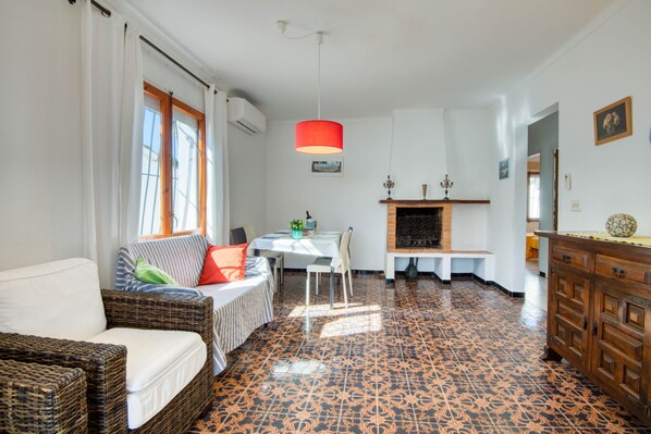Un salon comprenant un canapé, une table à manger et des chaises. On y trouve également une cheminée et un buffet en bois.